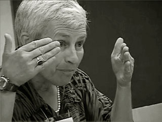 Picture of Cynthia Selfe at a 45-degree angle toward her right side. She holds her hands raised in front of her face.