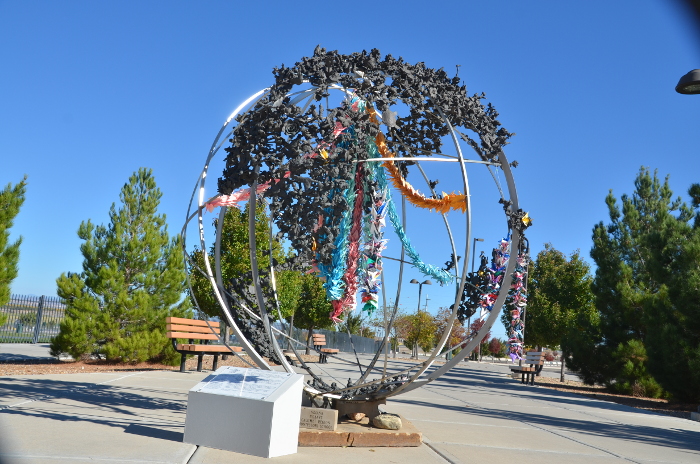 Photo of an open steel globe, with blue sky and trees in the background.