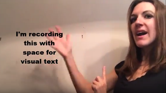 This figure shows me (a young woman with medium-length brown hair wearing a black shirt) rotating my right hand around visual text in the space to my right that reads, in black font, “I'm recording this with space for visual text.”